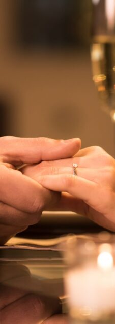 Closeup,Of,Couple,Hands,On,Restaurant,Table,With,Two,Glasses